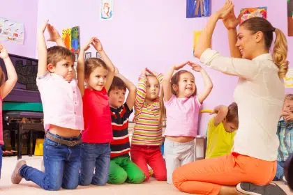 children in nursery copying acions of nursery nurse